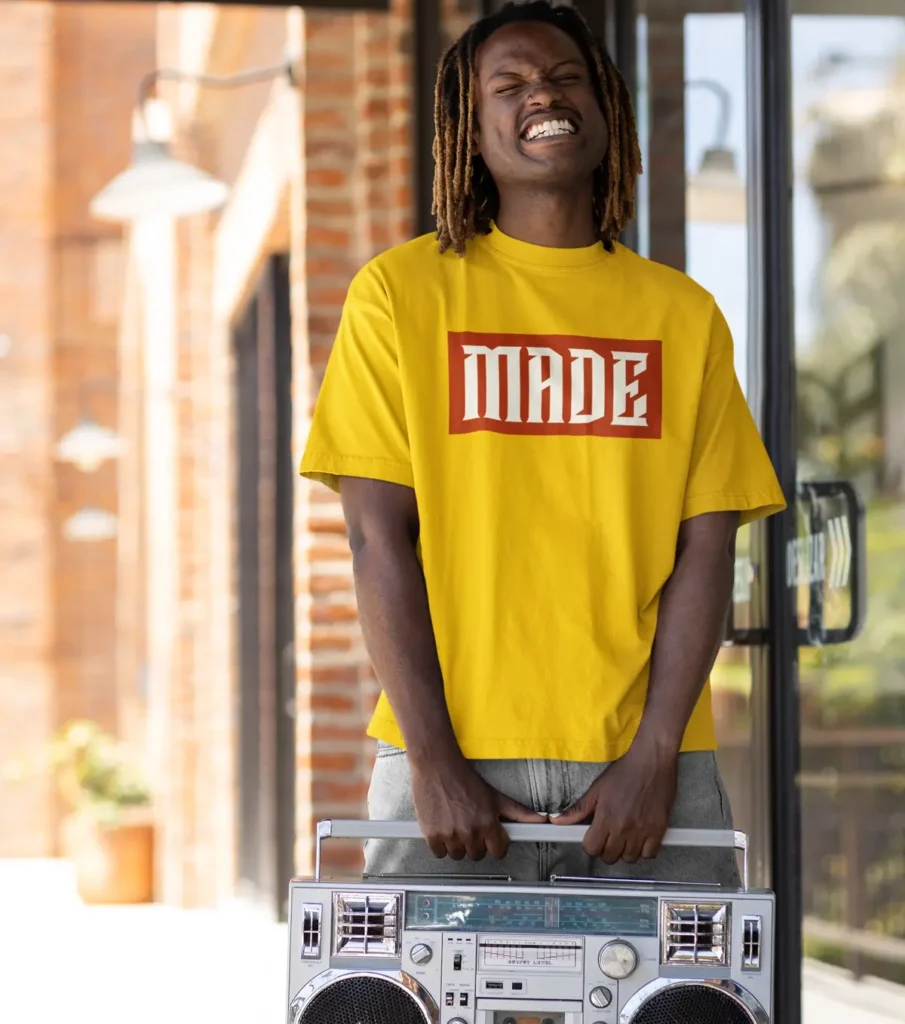 Man wearing a yellow graphic tee while posing with a boom box.